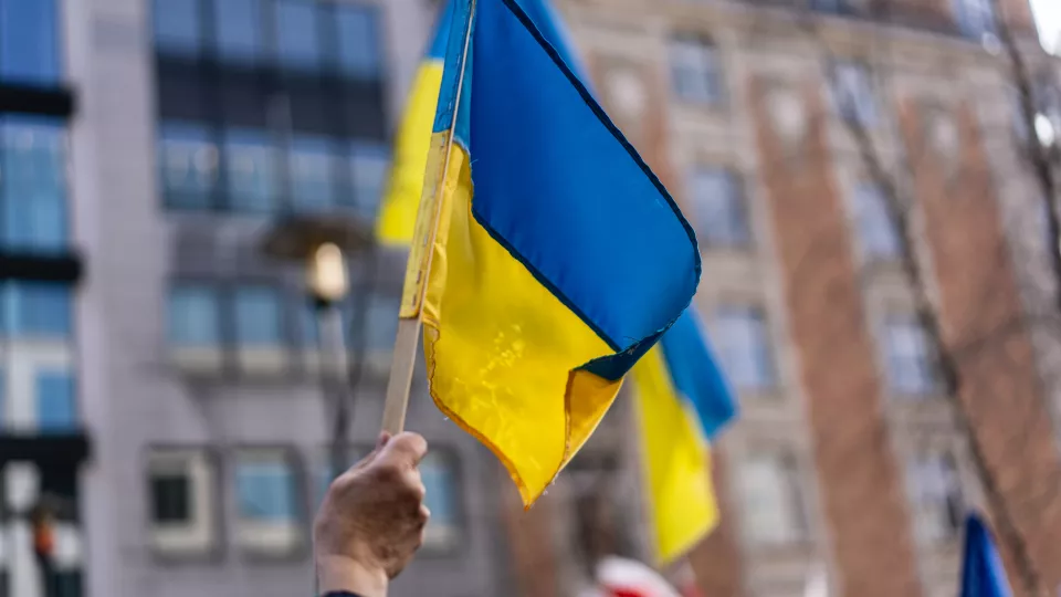Photo of a hand waving the Ukrainian flag.