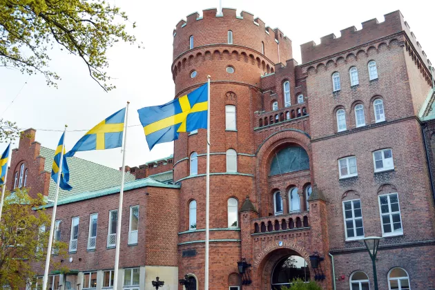 Photo of AF-borgen. A fort-like builiding made of bricks. The Swedish flag is waving.