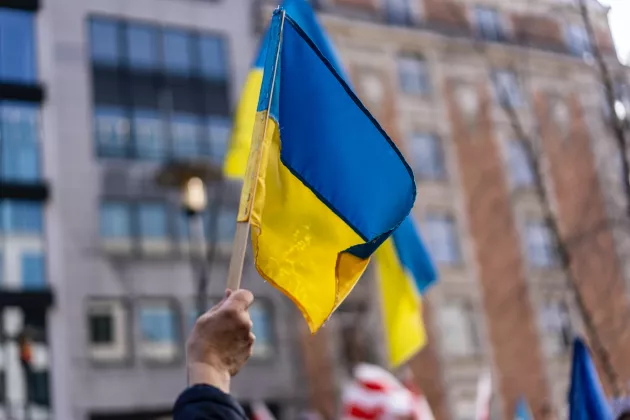 Photo of a hand waving the Ukrainian flag.