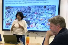 Manisha Anantharaman having a talk infront of a screen with a photo of a waste worker and trash