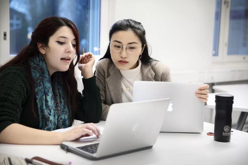 Students looking at each others laptops.
