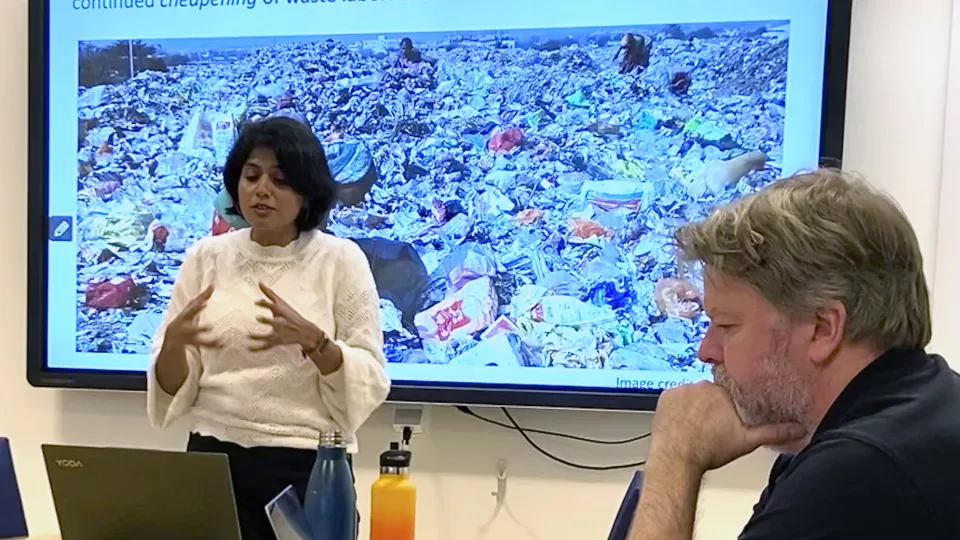 Bilden visar Manisha Anantharaman framför en skärm med bild på avfall och en avfallsarbetare