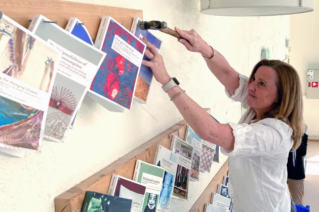 Pernilla Danielsson spikar upp en bok på en vägg.