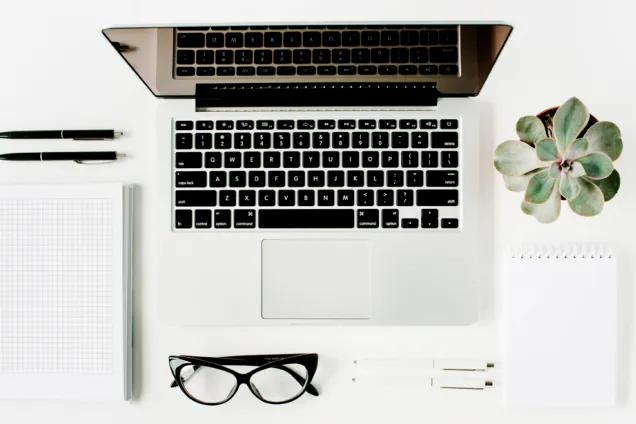 Skrivbord med dator och andra prylar.