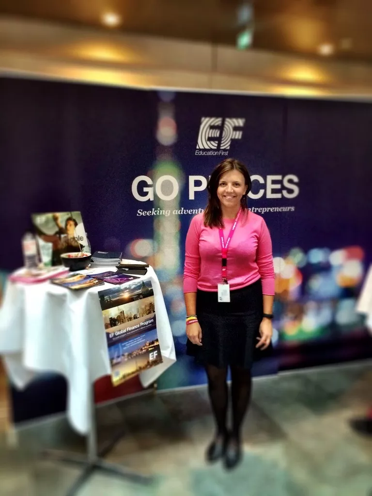 Foto på Stina Sandberg i en mässmonter. Hon har på sig en rosa EF-tröja.