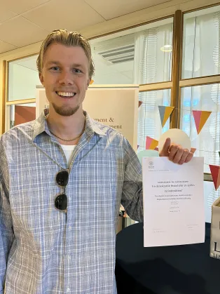 En student som håller i sin uppsats.