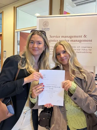 Två studenter som håller i sin uppsats.