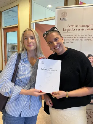 Två studenter som håller i sin uppsats.
