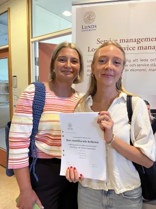 Två studenter som håller i sin uppsats.