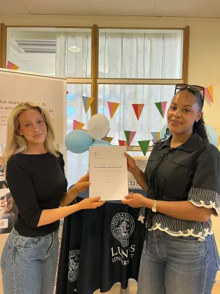 Två studenter som håller i sin uppsats.