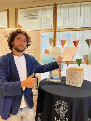 En student som håller i sin uppsats.